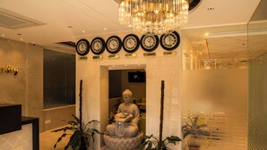 A reception area with a Buddha statue, clocks, and potted plants. - Hotel Urban Jade (Bengaluru)