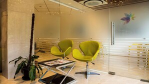 A reception area with two bright yellow chairs, a glass table with a magazine, and a potted plant. - Hotel Urban Jade (Bengaluru)