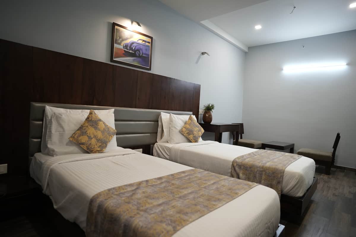 A hotel room with two beds, a wooden headboard, a small table, and a chair.
