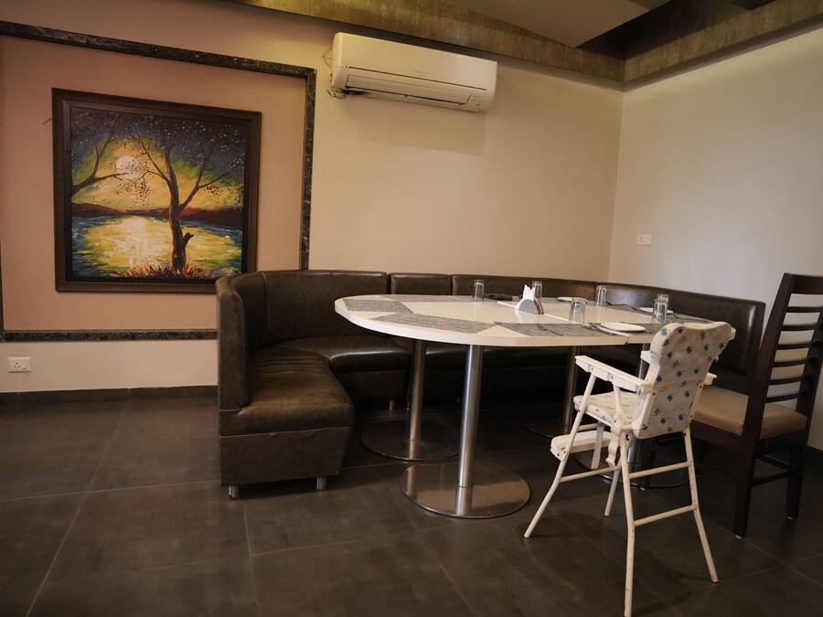 A dining area with a round table, chairs, and a painting on the wall.