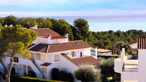 Una zona residencial costera con casas blancas, tejados de tejas rojas y vistas al mar.