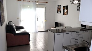 Una cocina moderna con una isla integrada, armarios blancos y un lavamanos de acero inoxidable.