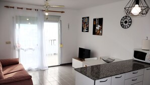 Una cocina moderna con una isla central, armarios blancos y un sofá marrón.