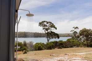 A shower with a view of a lake and trees.