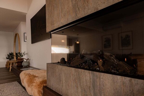 A modern living room with a fireplace, a fur throw, and a mirror on the wall.