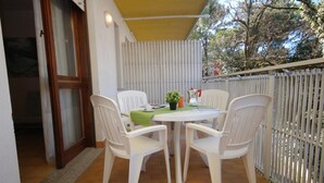 A balcony with a table and chairs, a potted plant, and a railing. - Elegant and well-located studio apartment (Lignano Sabbiadoro)