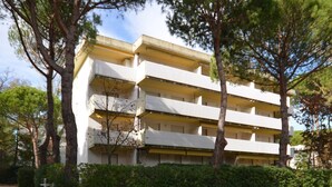 A multi-story building with balconies, surrounded by trees and greenery. - Elegant and well-located studio apartment (Lignano Sabbiadoro)