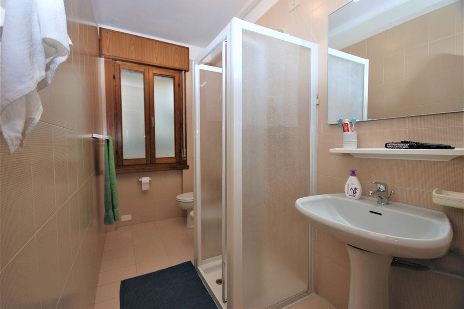 Een badkamer met douche, toilet en wastafel.