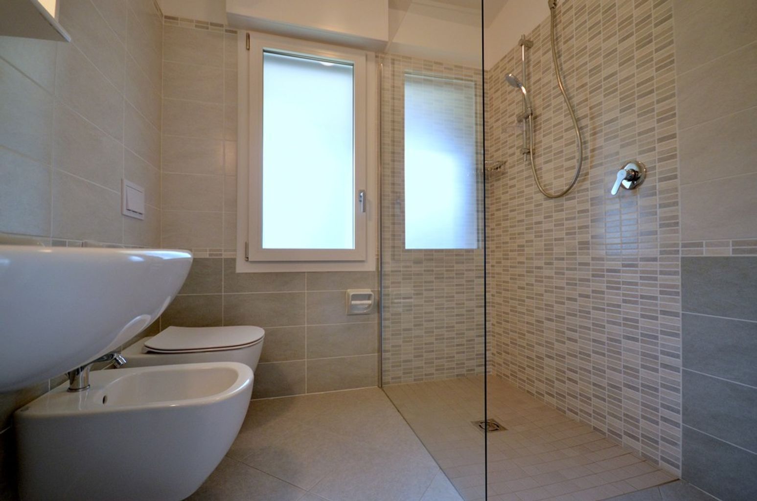 A modern bathroom with a glass shower enclosure, a toilet, and a sink.