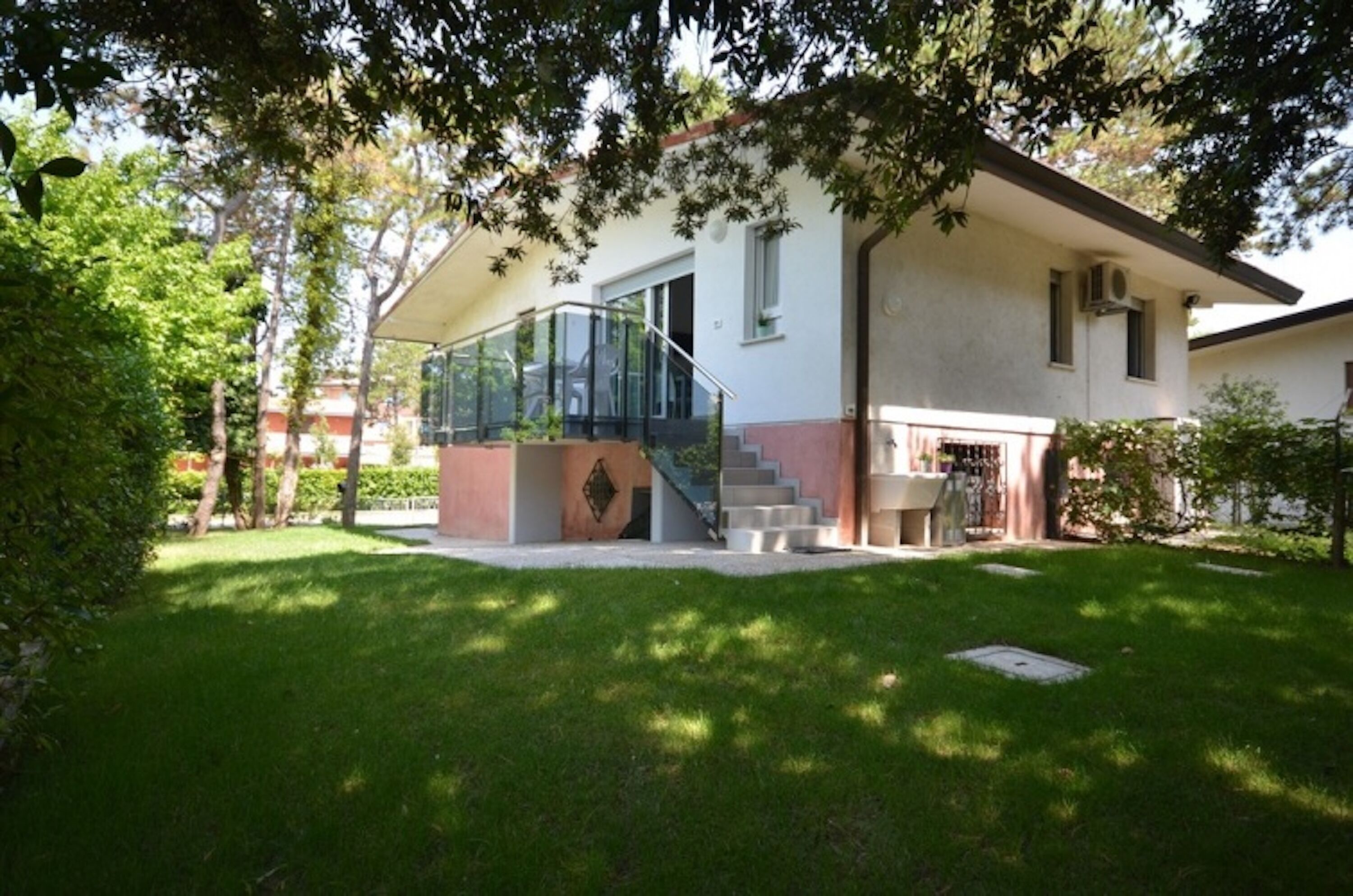 Ein modernes Haus mit einer gläsernen Wendeltreppe, die zu einem überdachten Außenbereich führt.