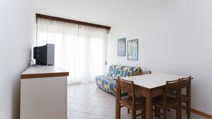 Ett kompakt bostadsutrymme med ett litet kök, en matplats och en soffa.