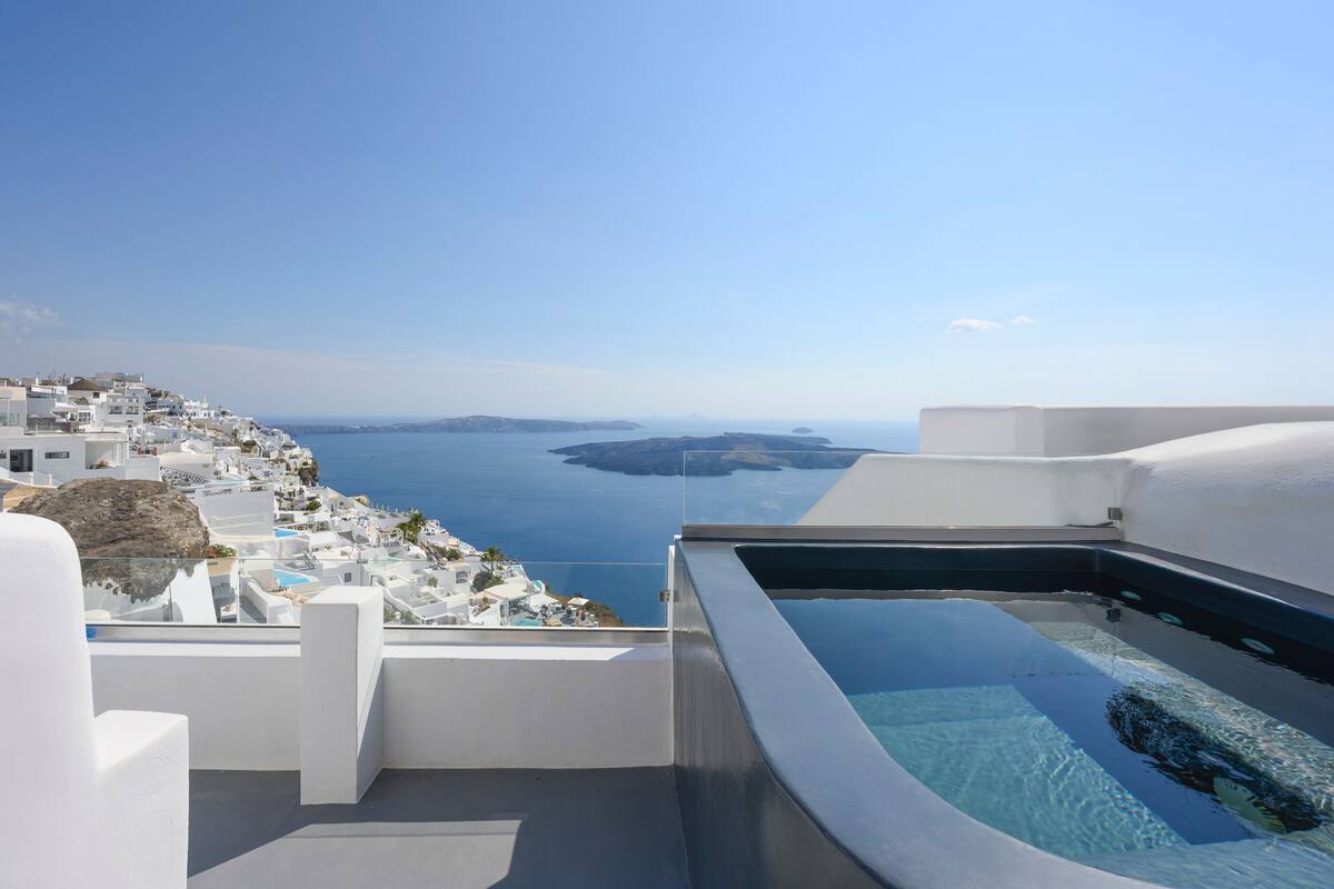 Piscina en la azotea con vista despejada a un pueblo costero y al mar.