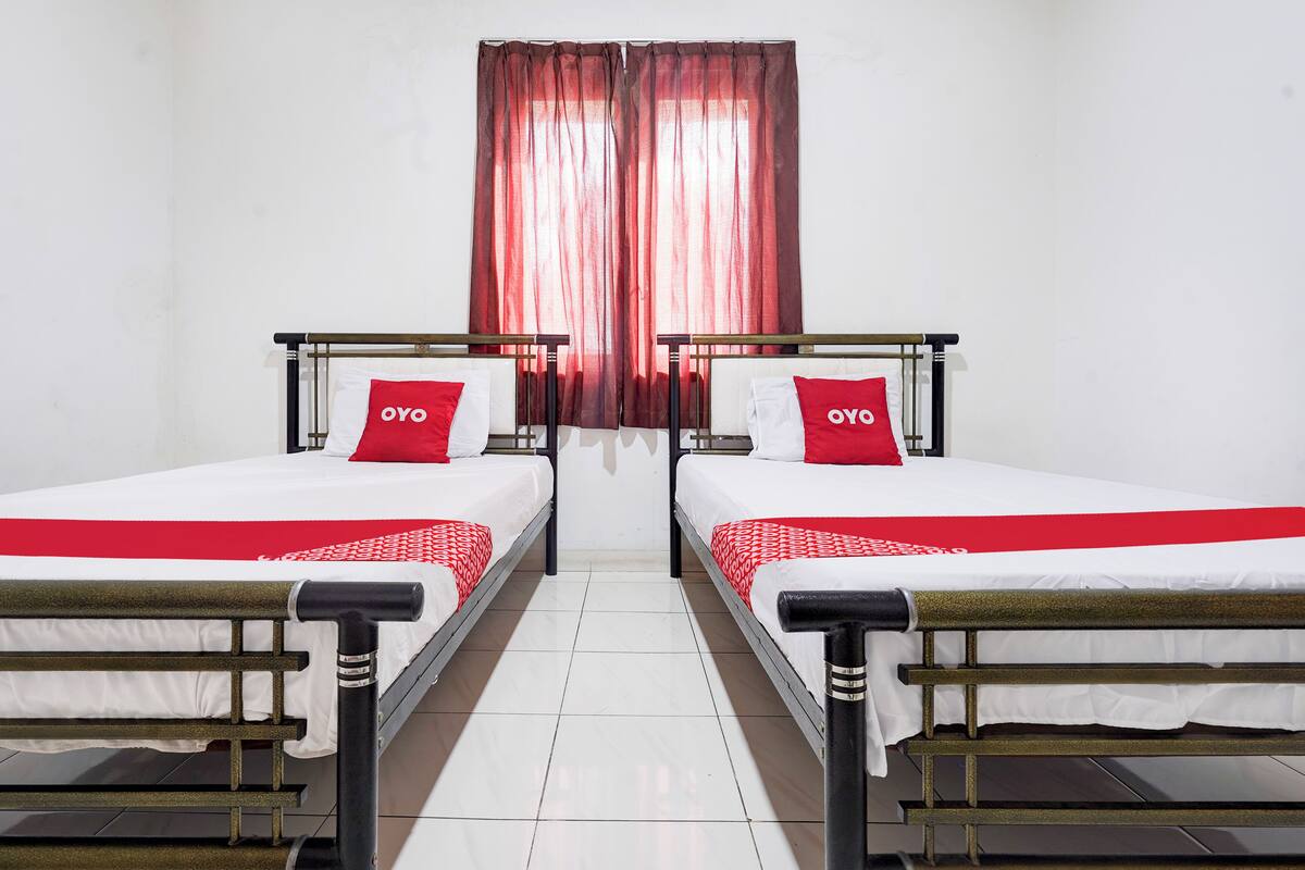 A hotel room with two beds, each with a red and white bedspread and matching pillows.