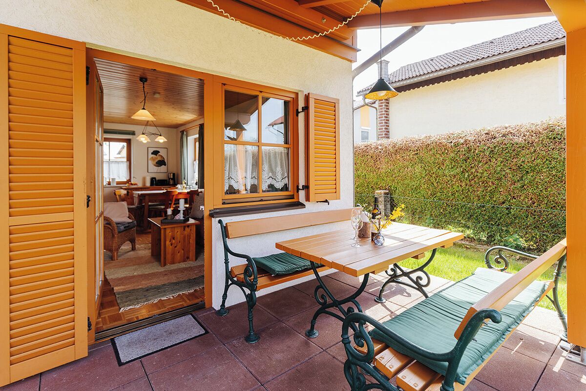 Un patio ouvert avec des meubles en bois, une table et un banc.