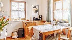 A cozy dining area with a wooden table, chairs, and a view of the outdoors through large windows. - Ferienhaus Nora (Sankt Kanzian am Klopeiner See)