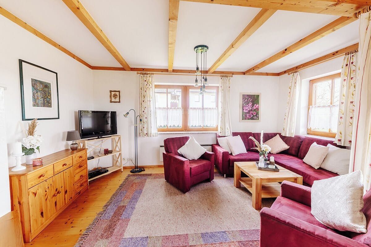 A cozy living room with a wooden ceiling, a television, a sofa set, and a coffee table.