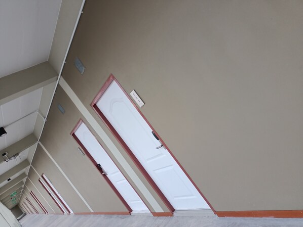 A corridor with multiple doors, each with a red frame and a white door. - The Peachhotel (Phetchaburi)