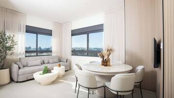 A modern living room with a sofa, coffee table, and dining table with chairs.