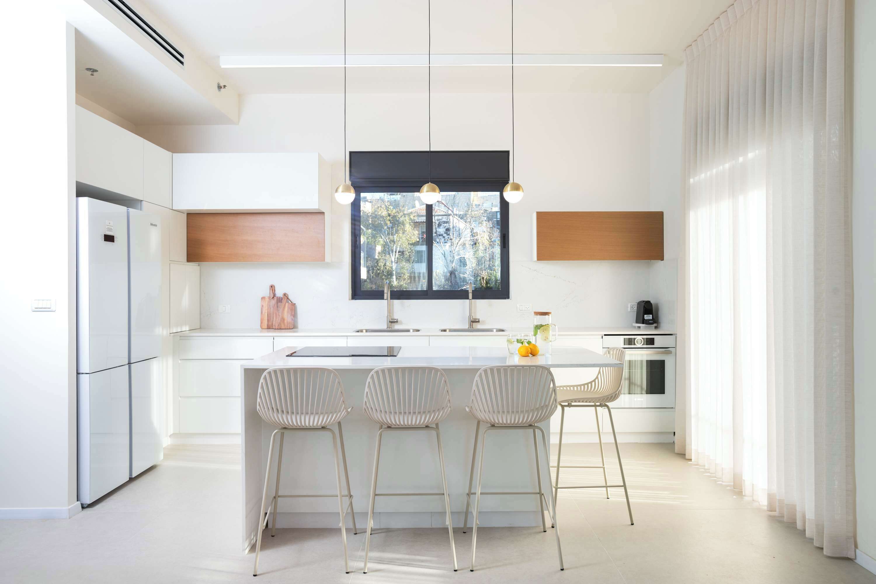 A modern kitchen with a central island, stainless steel appliances, and pendant lighting.