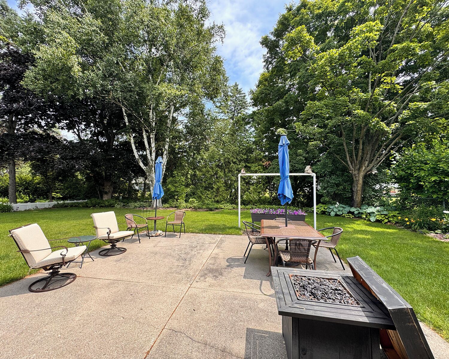 A patio area with outdoor furniture, a fire pit, and umbrellas.