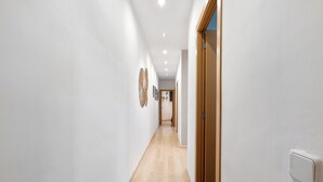 A narrow, well-lit hallway with wooden flooring and white walls.