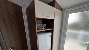 A compact kitchen with a white refrigerator, wooden cabinets, and a glass door leading to a balcony. - Wl34 Caravan Haggerston Castle Private Decking (Berwick-upon-Tweed)