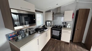 A modern kitchen with a microwave, toaster, coffee maker, and stove. - Wl34 Caravan Haggerston Castle Private Decking (Berwick-upon-Tweed)