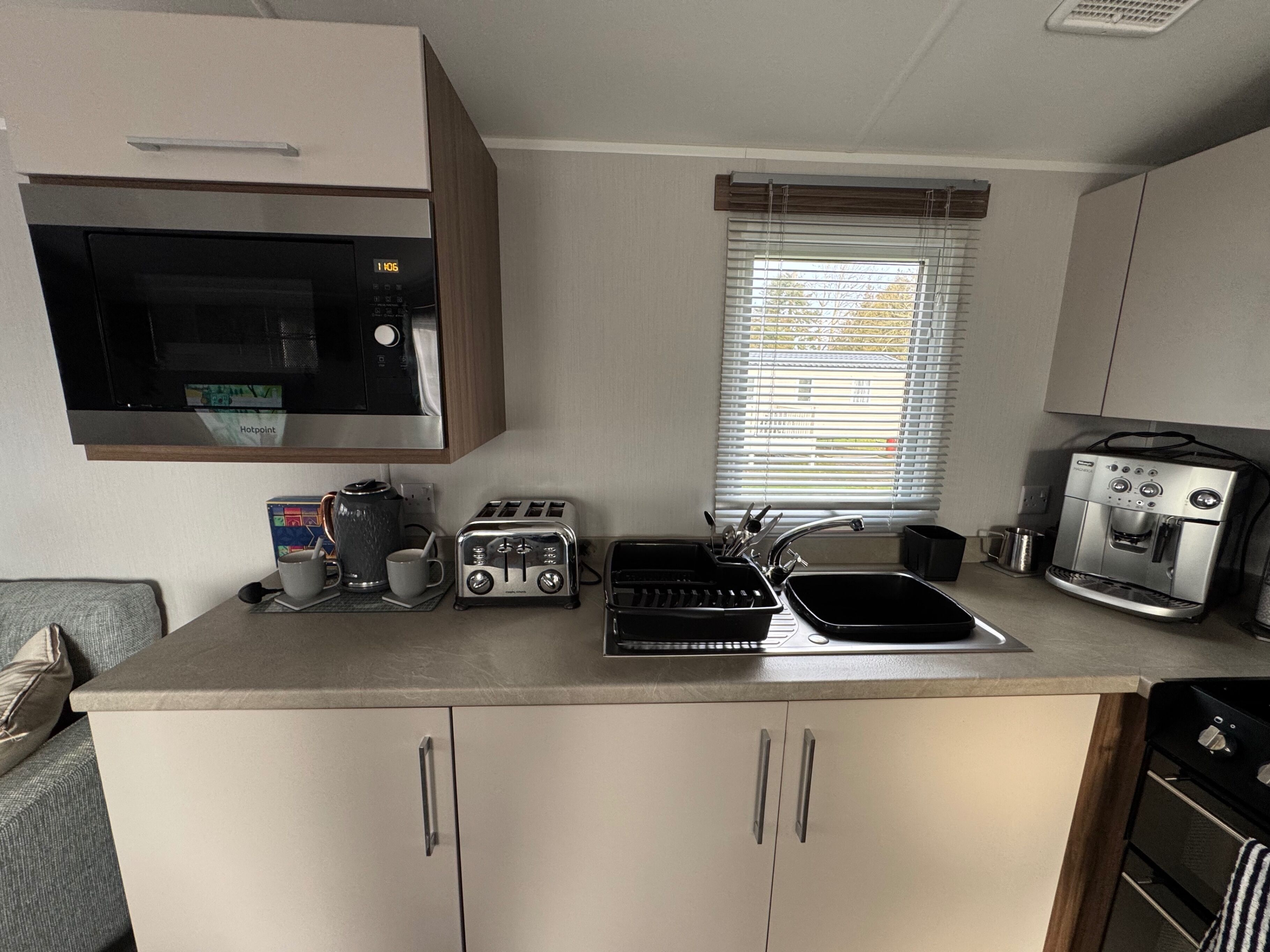 A compact kitchenette with a microwave, toaster, coffee maker, and espresso machine.