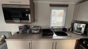 A compact kitchenette with a microwave, toaster, coffee maker, and espresso machine.
