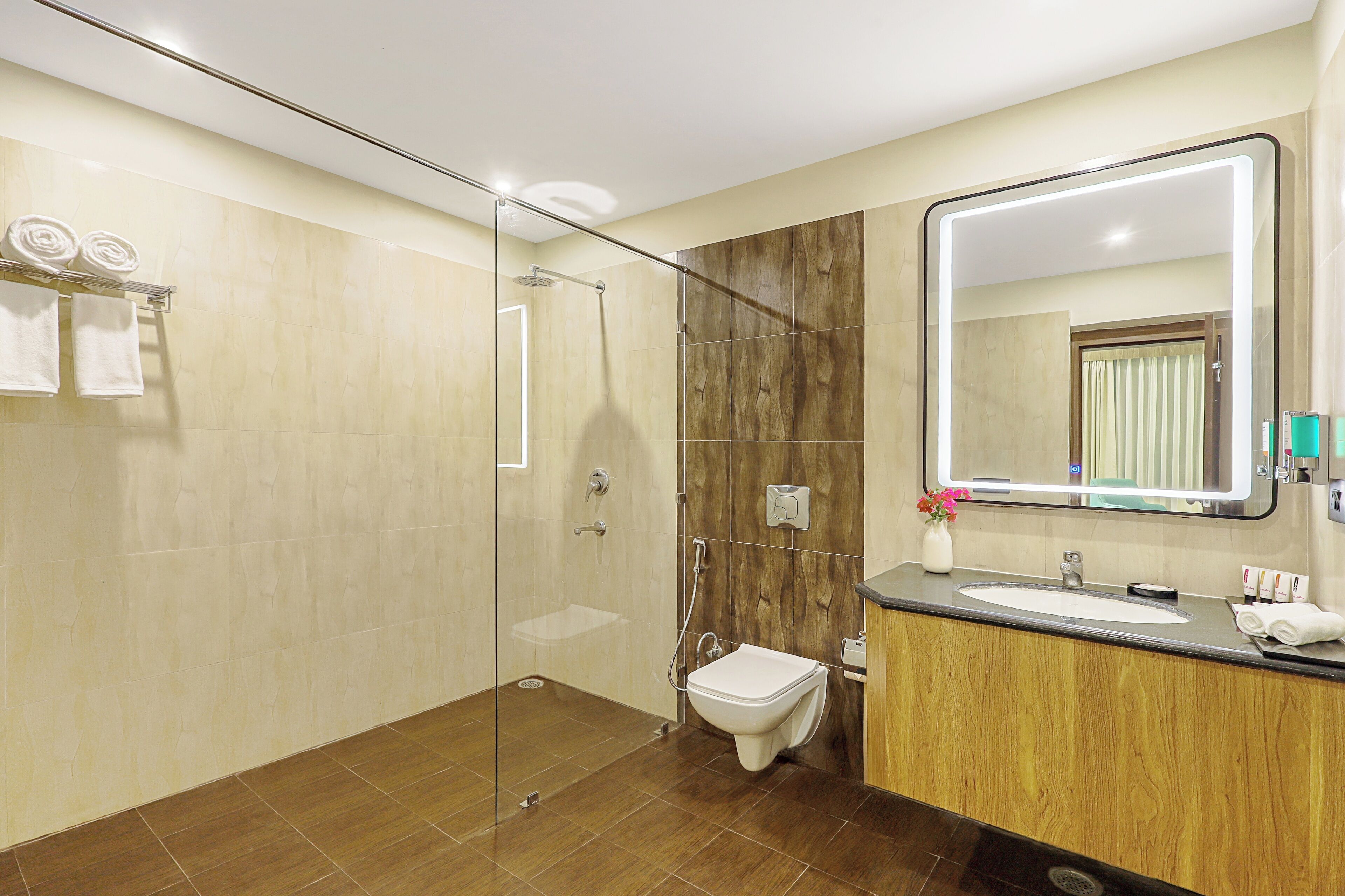 A modern bathroom with a glass-enclosed shower, a wooden vanity, and a large mirror.