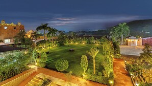 A well-maintained lawn with a pathway leading to a building, surrounded by palm trees and other greenery. - Sterling Bagh Ranthambore (Sawai Madhopur)