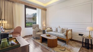 A hotel room with a sofa, armchair, coffee table, and a desk with a lamp. - Sterling Bagh Ranthambore (Sawai Madhopur)