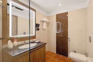 Un baño moderno con un espejo grande, un lavabo, un inodoro y una zona de ducha.