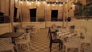 Un café al aire libre con suelo a cuadros, sillas y mesas de metal blanco.