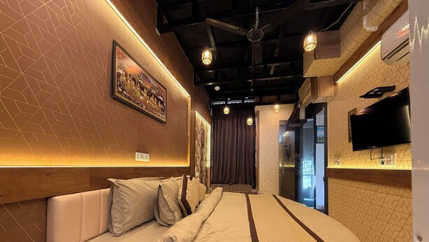 Una habitación de hotel moderna con una cama grande, un televisor y un ventilador de techo.