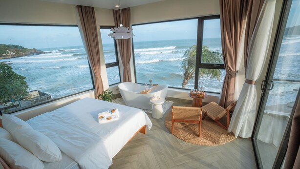 Une chambre spacieuse avec un grand lit, une baignoire et une vue sur l’océan.