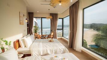 A spacious bedroom with a large bed, a dining area, and a view of the beach.