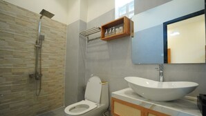 Une salle de bain moderne avec une douche en pierre, des toilettes, un grand lavabo et un miroir.