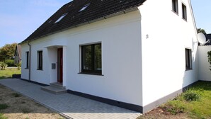 Un bâtiment blanc avec un toit foncé, une porte rouge et une antenne parabolique.