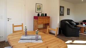 Un coin repas avec une table en bois, des chaises, un vase de fleurs et un meuble en bois contenant des haut-parleurs.