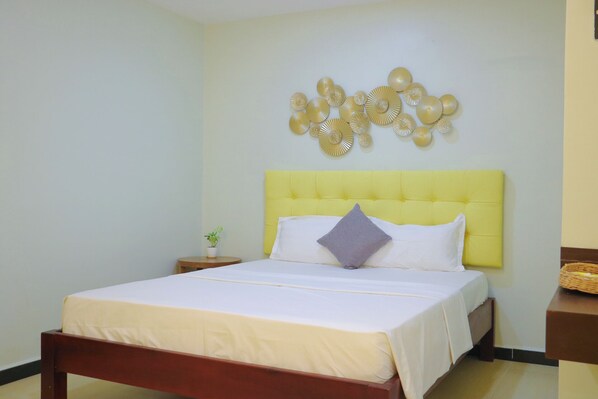 A neatly made bed with a yellow headboard, white bedding, and a single pillow. - The Kool by Sanctuary Residence (Siem Reap)