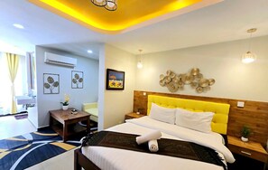 A hotel room with a bed, bedside tables, a desk, and a chair. There is a window with curtains, an air conditioning unit, and wall decorations. - The Kool by Sanctuary Residence (Siem Reap)