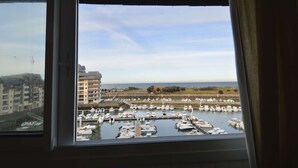 A marina with boats docked, a clear sky, and buildings in the background. - Aux beaux coquillages, sea and harbor view (Courseulles-sur-Mer)