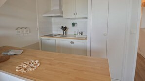 A compact kitchen with white cabinets, a wooden countertop, and a built-in stove. - Aux beaux coquillages, sea and harbor view (Courseulles-sur-Mer)