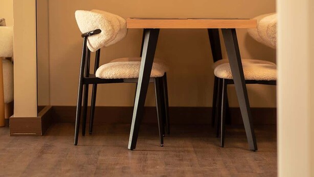 Een eetruimte met een houten tafel en twee stoelen met zwarte poten en beklede zitplaatsen.