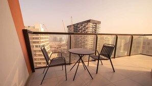Een balkon met een tafel en stoelen, uitzicht op een stadsgezicht en een gebouw in aanbouw.