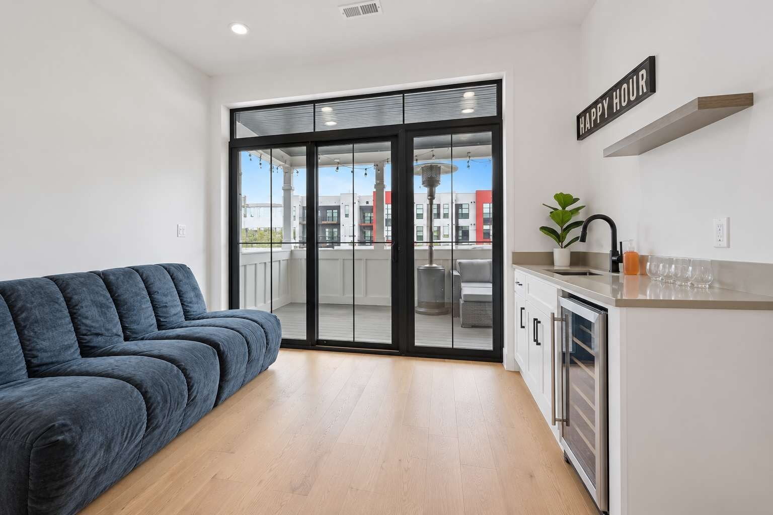 Un apartamento moderno con sofá, zona de cocina y puerta corrediza de vidrio que da a un balcón exterior.