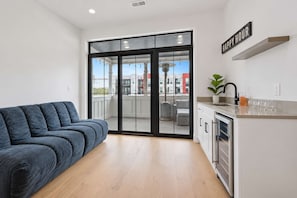 Un apartamento moderno con sofá, zona de cocina y puerta corrediza de vidrio que da a un balcón exterior.