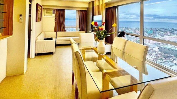 Une chambre d’hôtel moderne dotée d’un coin repas, d’un canapé et d’une grande fenêtre donnant sur la ville.
