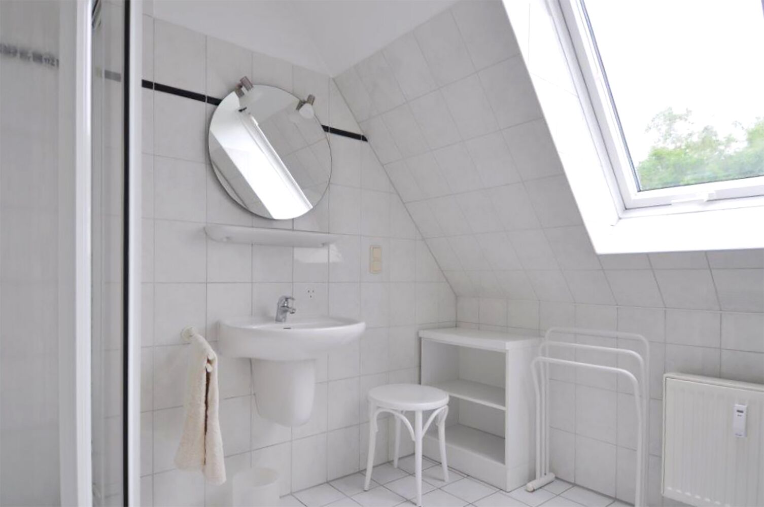 A modern bathroom with a skylight, a sink, a mirror, and a toilet.